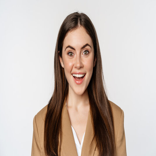 Close up portrait of enthusiastic corporate woman, looking amazed and excited at camera, standing in suit over white background.